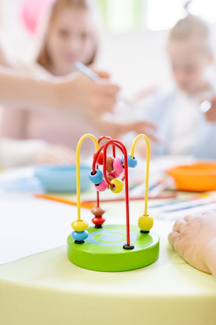 Close-up of a bead toy with children playing in an educational environment.